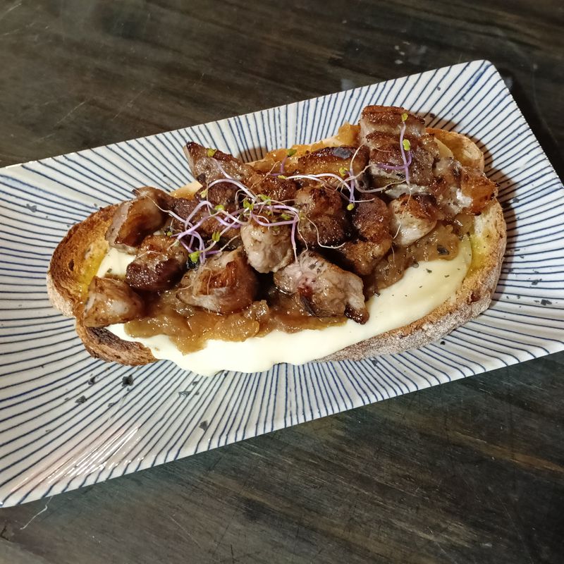 Tosta de largarto de cerdo con tetilla y cebolla caramelizada, aderezado con queso azul