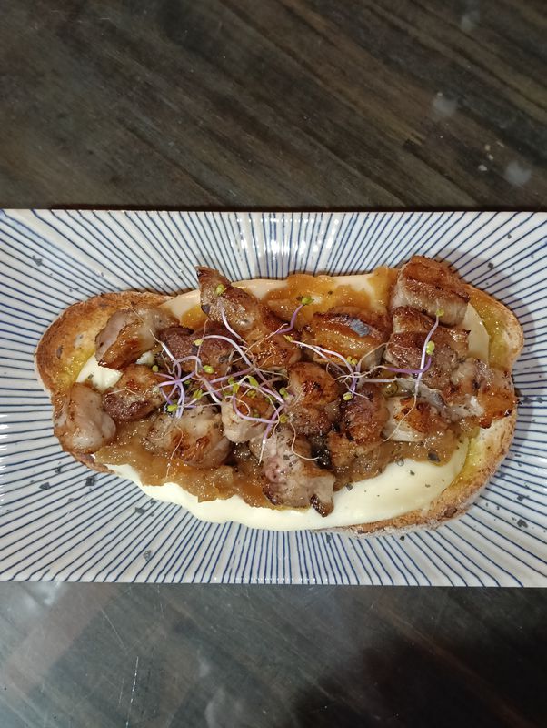 Tosta de largarto de cerdo con tetilla y cebolla caramelizada, aderezado con queso azul